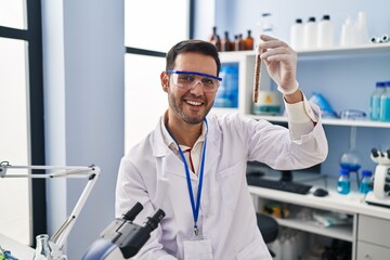 Poster - Young hispanic man scientist holding test tube at laboratory