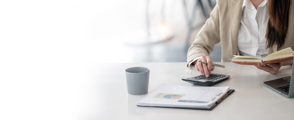 Wall Mural - businesswoman using calculator working at office with document on her desk, doing planning analyzing the financial report, business plan investment,