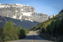 Car Driving On Scenic Icefields Parkway Between Banff National Park And Jasper National Park With Snowy Mountains In Distance, Alberta, Canada