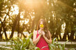 © Cavan Images - Woman smiles while holding a sunflower