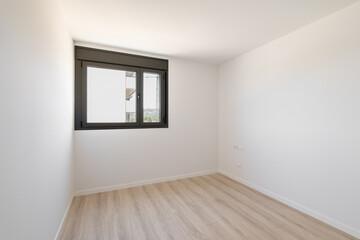 Wall Mural - Small empty room without furniture. The floor is new light wood laminate. A window made of black plastic for airing the room. Daylight enters through the frosted glass in the window.