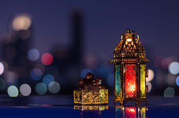 Wall Mural - Lantern and small plate of dates fruit with night sky and city bokeh light background for the Muslim feast of the holy month of Ramadan Kareem.