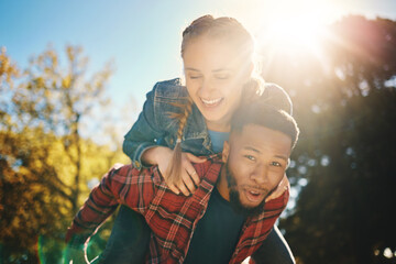 Interracial couple, sunshine and piggyback in park, summer and outdoor date together for happiness, smile and nature. Happy man carrying woman in garden for love, care and relax for diversity partner