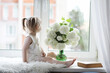 © alexkich - A little girl is sitting on the windowsill. A bouquet of flowers in a vase by the window and a girl sniffing flowers. A little princess in a white dress with a bouquet of white flowers by the window.