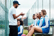 Netball plan, sports team and coach explain game strategy, teamwork collaboration talk or planning competition idea. Coaching athlete, substitute bench and group of people listen to fitness challenge