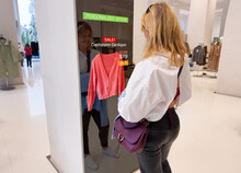 Woman Viewing Advanced Mirror Display In Retail Store Showing Personalized Offers To Customers
