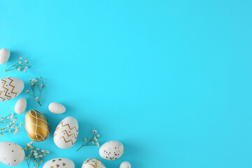 Wall Mural - Easter concept. Top view photo of white gold eggs and gypsophila flowers on pastel blue background. Flat lay with empty space. Easter invitation card idea.