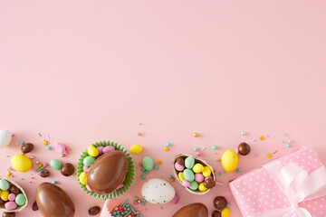 Wall Mural - Sweet Easter concept. Top view photo of chocolate eggs dragees sprinkles and present gift box on isolated pastel pink background with copyspace. Holiday card idea
