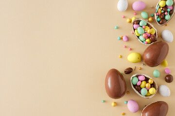 Wall Mural - Easter sweets concept. Top view photo of chocolate eggs dragees sprinkles on isolated beige background with copyspace
