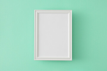 Top view photo of white frame on isolated turquoise background with blank space in the middle