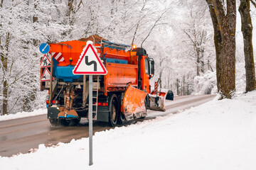 Snow ploughing truck cleans the forest road