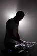 © hurricanehank - Silhouette of club dj mixing techno music. Young white man perfroming as a disc jockey on party in dark night club