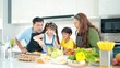 © M Stocker - Happy Asian family in the kitchen cooking together healthy. Parents teach little children healthy habits and how to mix vegetables in salad bowl