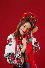 Wall Mural - Portrait of ukrainian woman in traditional ethnic clothing and floral red wreath with handkerchief on viva magenta studio background. Ukrainian national embroidered dress call vyshyvanka