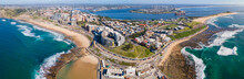 Panoramic Aerial Drone View Of The Harbour City Of Newcastle, NSW, Australia As A Cargo Ship Enters Newcastle Harbour On A Sunny Day 