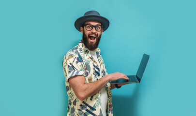 Wall Mural - Young crazy bearded charismatic man. Shocked or surprised expression. Laptop concept. Funny promotion poster. Programmer, web developer holding a laptop in his hands and looking at the camera