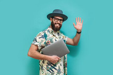 Young crazy bearded charismatic man. Shocked or surprised expression. Laptop concept. Funny promotion poster. Programmer, web developer holding a laptop in his hands and looking at the camera