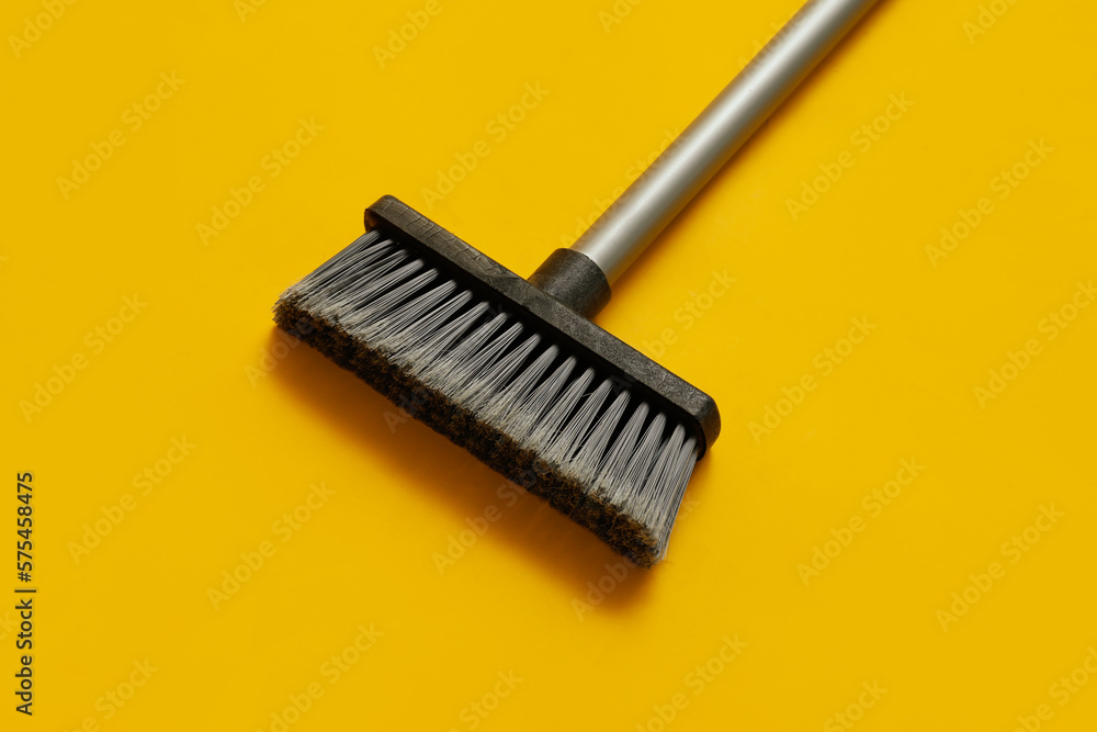 Plastic cleaning broom on yellow background