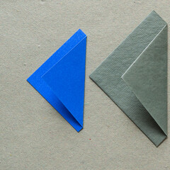 Sticker - folded blue and green paper triangle shapes on rough green paper