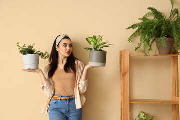 Canvas Print - Young woman with green houseplant near beige wall