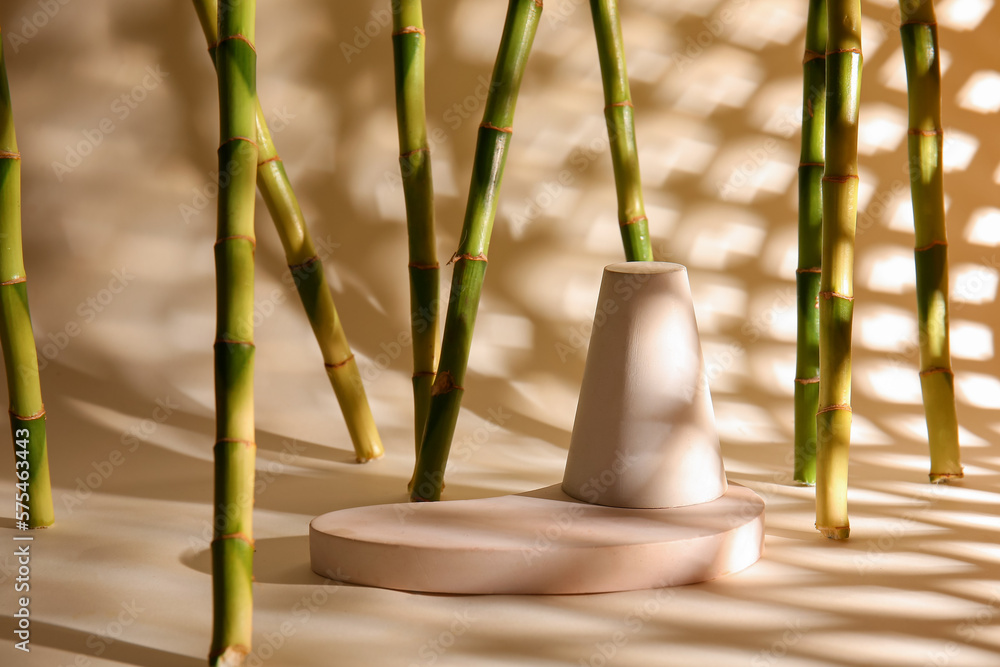 Green bamboo stems and plaster podiums on beige background