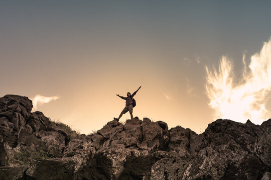 hiker with arms up standing on the top of the mountain - successful man enjoying triumph - sport and