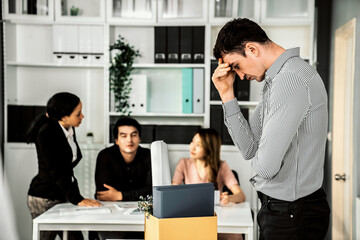 Depressed and disappointed employee packing his belongings after being fired for not being competent. Gossiped by his colleagues behind his back. Layoff due to economic depression.