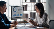 © wichayada - Two business people talk project strategy at office meeting room. Businessman discuss project planning with colleague at modern workplace while having conversation and advice on financial data report.