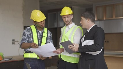 Wall Mural - Architect discussing blueprints on laptop with construction manager Engineer talking to contractor consultant on construction site about construction project and business workflow in new building