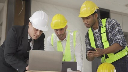 Wall Mural - Architect discussing blueprints on laptop with construction manager Engineer talking to contractor consultant on construction site about construction project and business workflow in new building