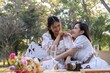 © Natee Meepian - Two beautiful Asian female besties cuddle, sharing a special moment together, and enjoy a picnic feeling friendly