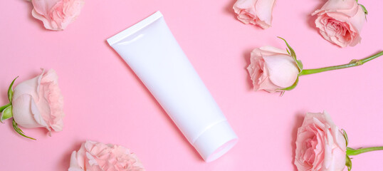 white empty cosmetic tube, on a pink background with delicate pink roses. natural cosmetics with ros