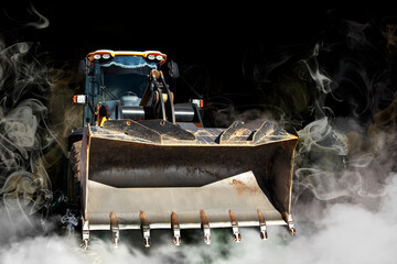 Wall Mural - Bulldozer or loader in smoke on a dark background. Powerful wheel loader or bulldozer with a large bucket. Rental of construction equipment.