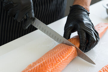 Wall Mural - Japanese chef cleaning salmon. A worker cutting salmon on a board.