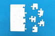 ©  DENIS   - The game, a lot of white puzzle pieces lie on a blue background.