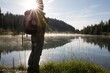 © Cavan Images - Hiker pauses at edge of mountain lake, sunrise