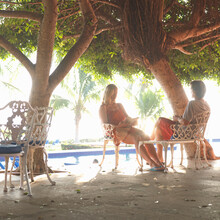 Couple Relax On Outdoor Patio Under Tree