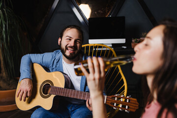 Wall Mural - Hispanic couple playing guitar, Girlfriend and boyfriend having fun at home at night in Mexico Latin America