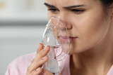 Fototapeta Łazienka - Sick young woman using nebulizer on blurred background, closeup. Space for text