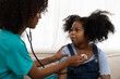 © amorn - Female doctor examining kid child girl by stethoscope at hospital