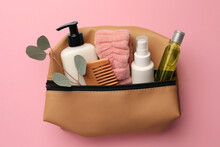 Preparation For Spa. Compact Toiletry Bag With Different Cosmetic Products And Eucalyptus On Pink Background, Top View