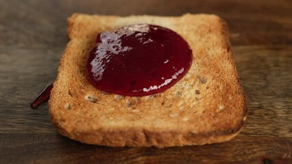 Wall Mural - Pour jam on toast bread, close up. Perfect traditional breakfast