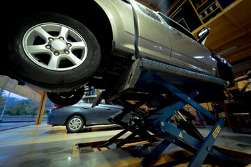 Wall Mural - Car on hydraulic lift in auto repair shop