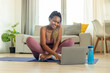 © Prostock-studio - Smiling black woman in sports clothes watching fitness videos on internet using laptop, sitting on fitness mat at home