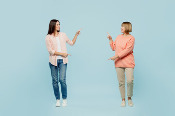 Wall Mural - Full body cheerful cool confident elder parent mom with young adult daughter two women together wear casual clothes point fingers on each other isolated on plain blue background. Family day concept.