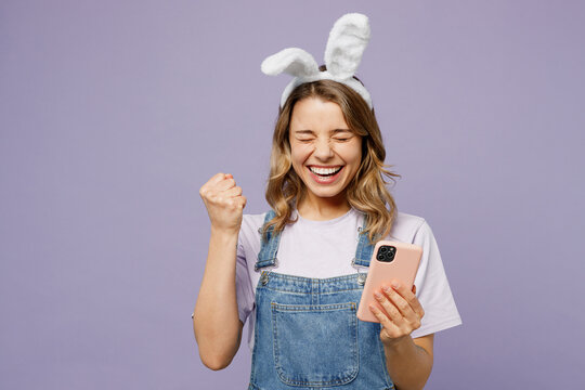 young fun woman wearing casual clothes bunny rabbit ears hold in hand use mobile cell phone do winne