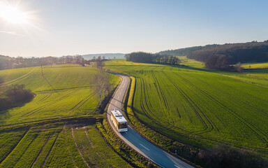 high angle view of bus driving on the winding road through the fields in the countryside under the b