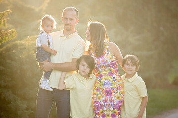 Sticker - Beautiful family, mother, father and three kids, boys, having familly outdoors portrait taken on a sunny spring evening, beautiful blooming garden, sunset time