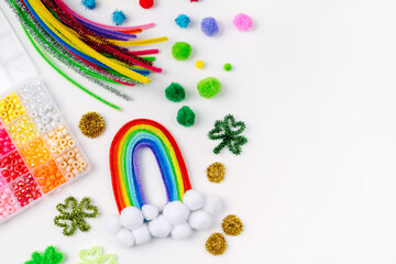 Rainbow and clover made of beads and pipe cleaners with different multi-colored  materials for DIY art activity for kids. Cute children's crafts of St Patrick's Day. Creativity and hobby.