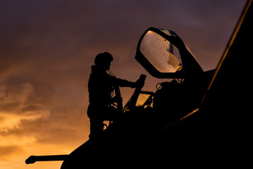 Wall Mural - Fighter pilot silhouette at sunset looking like Top Gun